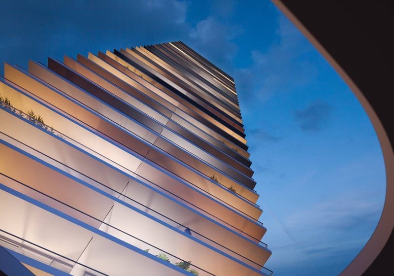 Night architectural view looking up at 2000 Ocean, Hallandale Beach, Florida, with illuminated stacked balconies and curved entry canopy, showcasing luxury and ultra luxury preconstruction condos.