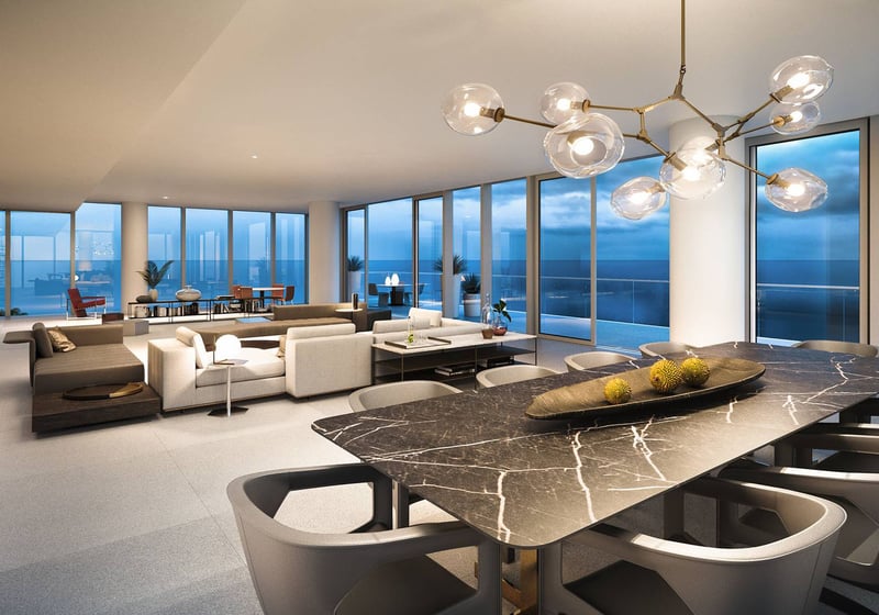 2000 Ocean open-concept living and dining room with designer chandelier, black marble table and wraparound glass facing the Atlantic in Hallandale Beach, South Florida, featuring luxury and ultra luxury preconstruction condos.