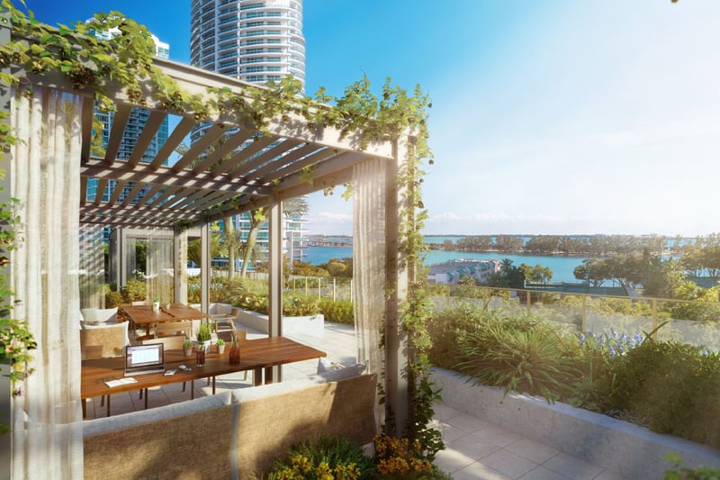2200 Brickell rooftop lounge with vine-covered pergola, coworking tables and waterfront bay views in Brickell, Miami, featuring luxury and ultra luxury preconstruction condos outdoor amenity terrace.