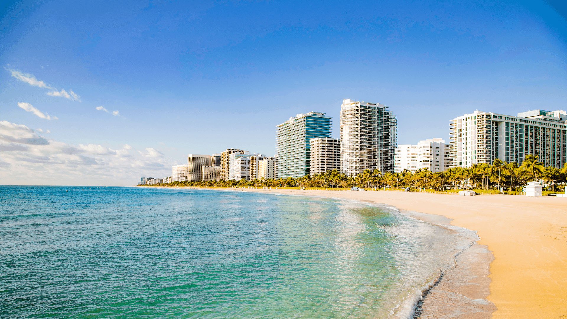 Beachfront shoreline near Alma Bay Harbor in Bay Harbor Islands, Miami, highlighting the coastal lifestyle of luxury and ultra luxury preconstruction condos with calm water, soft sand and nearby towers.