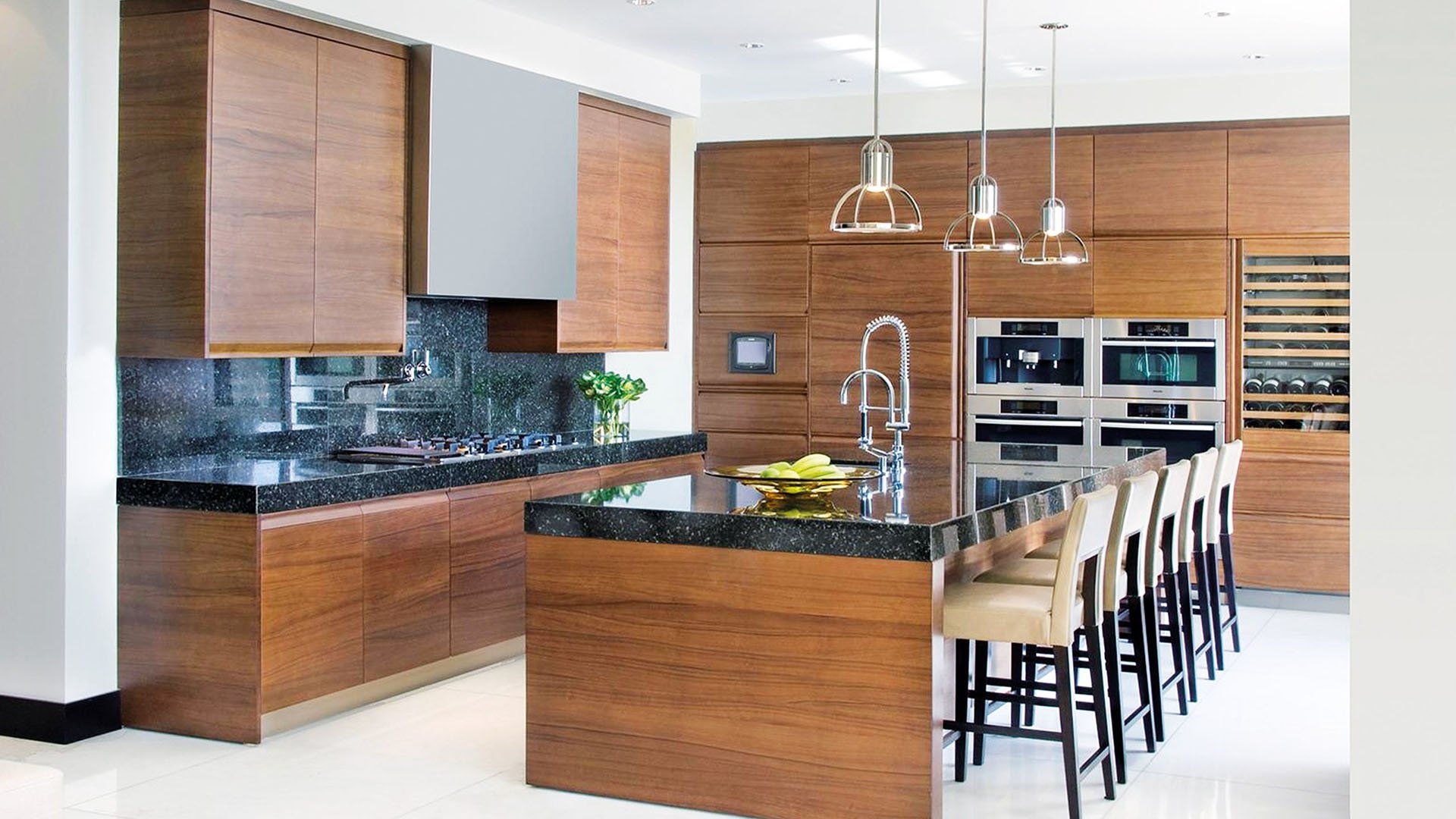 Chef kitchen with warm wood cabinetry, breakfast bar seating and built-in wine storage at Apogee in South Beach, showcasing luxury and ultra luxury condos finishes.