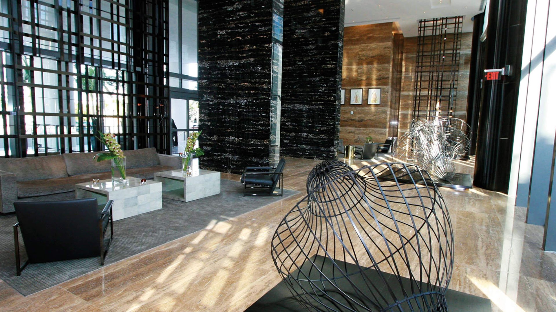 Designer lobby at Apogee in South Beach with black marble columns, sculpture seating accents and sunlit lounge space, reflecting luxury and ultra luxury condos design.
