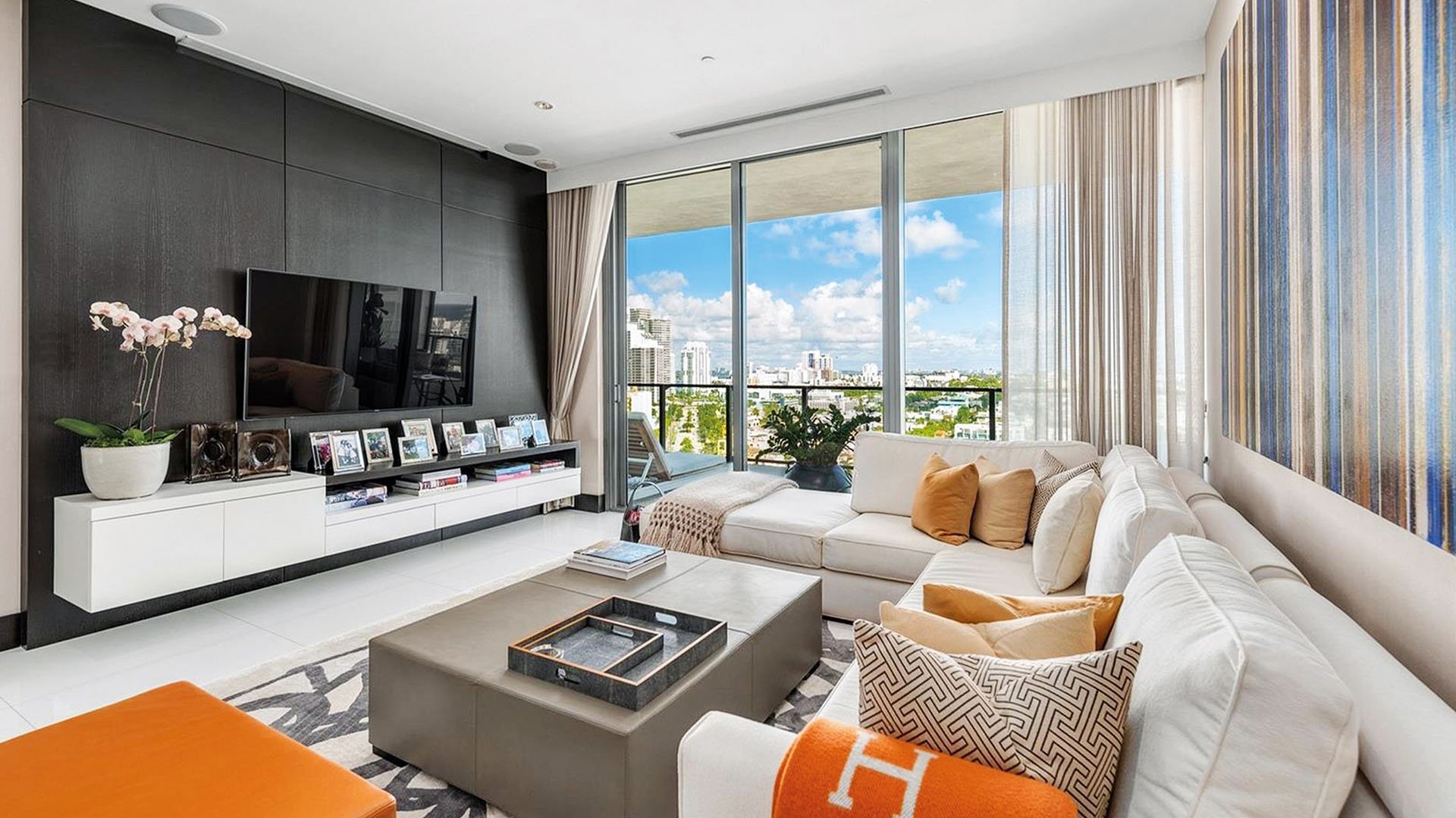 Stylish family room with a media wall, plush sectional and city-view balcony at Apogee in South Beach, highlighting luxury and ultra luxury condos interior design.