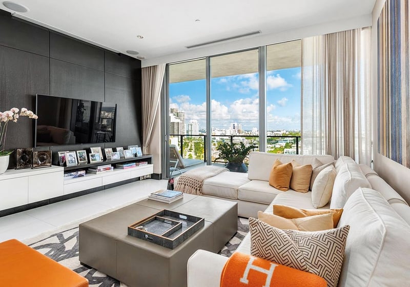 Stylish family room with a media wall, plush sectional and city-view balcony at Apogee in South Beach, highlighting luxury and ultra luxury condos interior design.