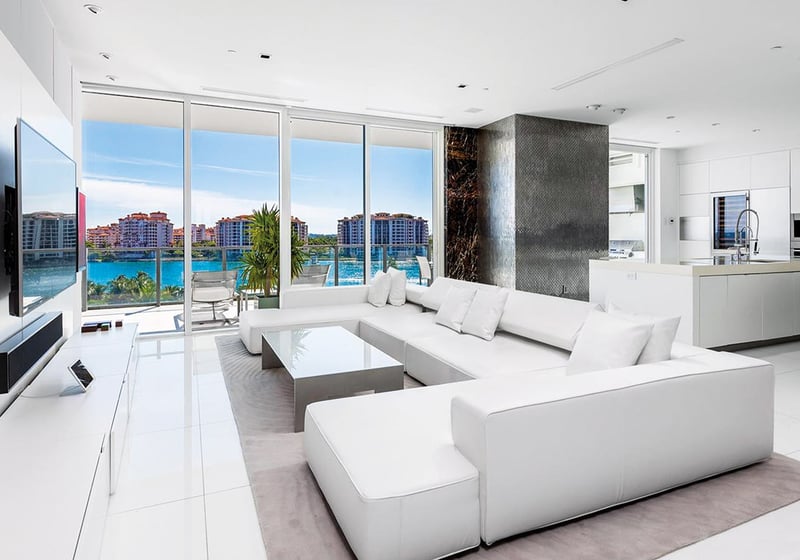 Open-plan living room and chef kitchen with white finishes, floor-to-ceiling glass and water views at Apogee in South Beach, showcasing luxury and ultra luxury condos interiors.