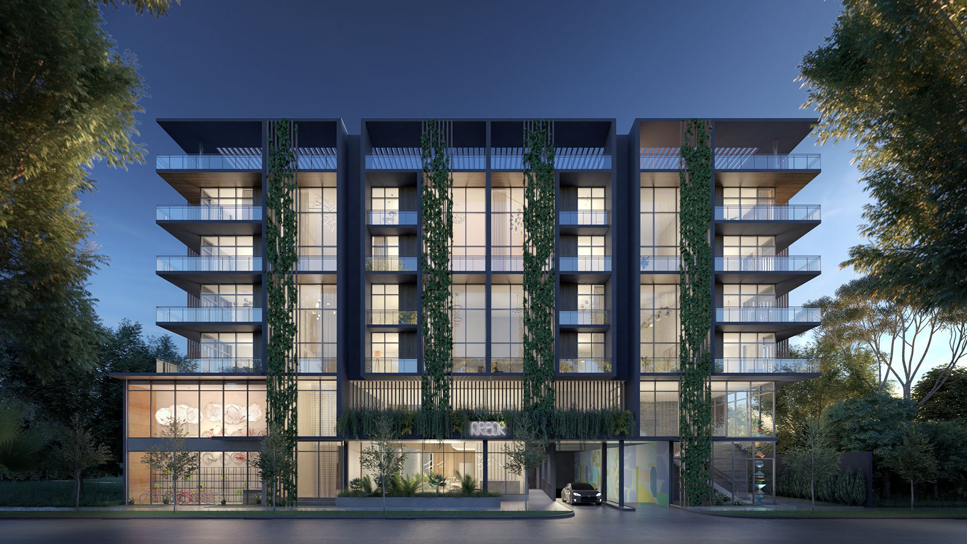 Dusk front exterior of Arbor in Coconut Grove with a dramatic porte cochere, vertical greenery and illuminated lobby spaces, showing luxury and ultra luxury condos with boutique curb appeal.