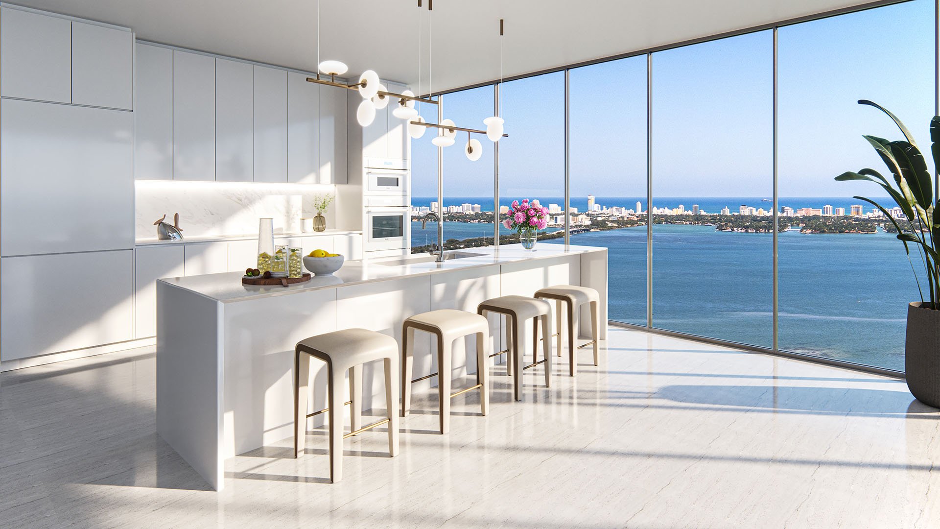 Aria Reserve Edgewater Miami modern kitchen with white cabinetry and oversized island, floor-to-ceiling windows framing Biscayne Bay views, showcasing luxury and ultra luxury preconstruction condos with chef-grade appliances.