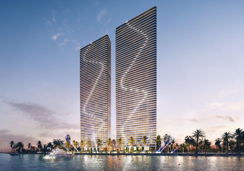 Aria Reserve Edgewater Miami skyline render of twin towers glowing at sunset over Biscayne Bay, palm-lined waterfront and marina, featuring luxury and ultra luxury preconstruction condos in Miami.