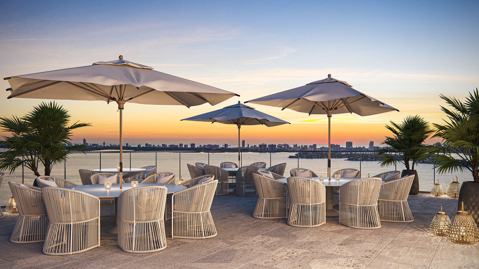 Aria Reserve Edgewater Miami rooftop dining terrace at sunset overlooking Biscayne Bay, featuring luxury and ultra luxury preconstruction condos with outdoor seating, umbrellas, and skyline water views.