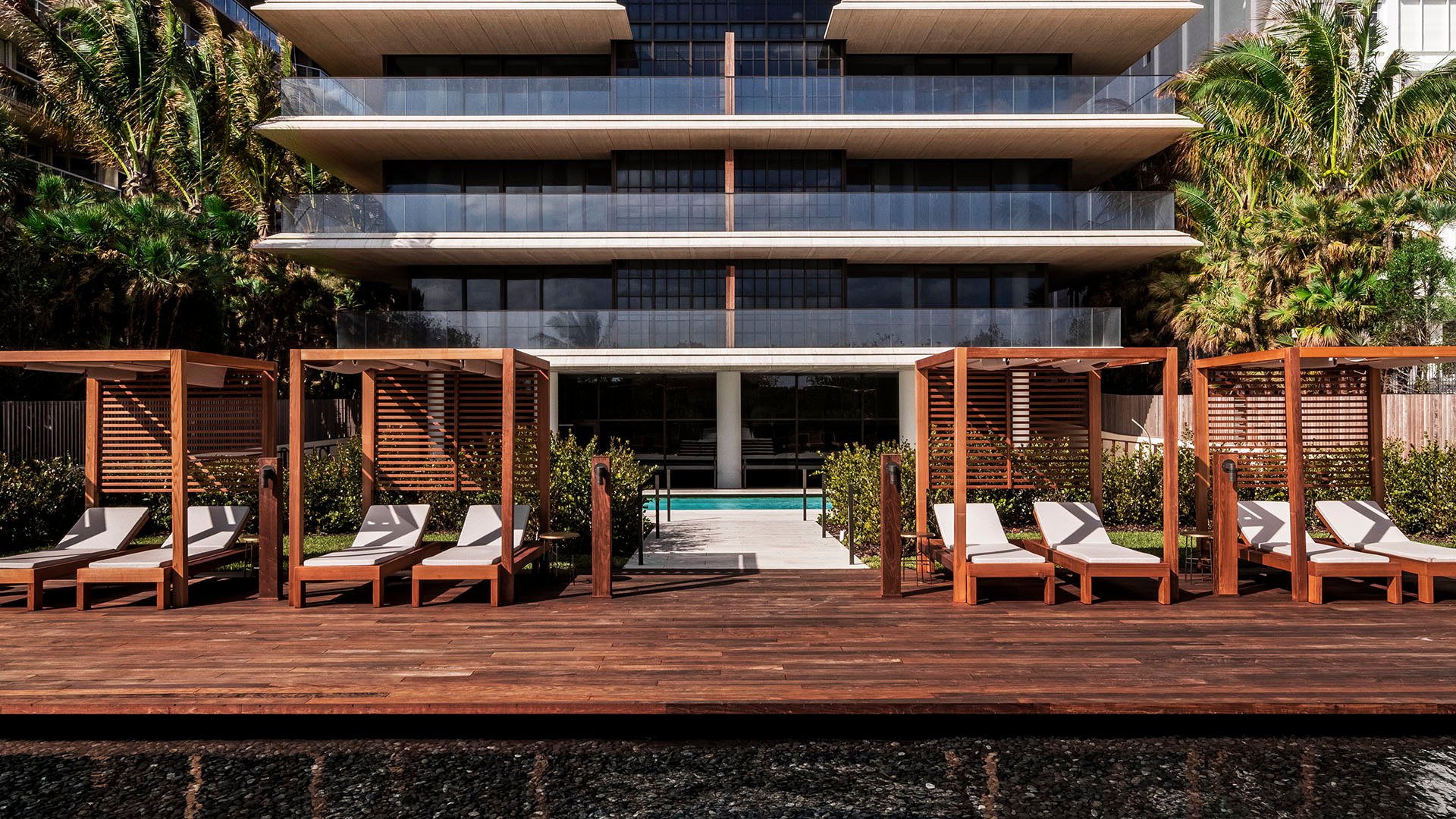 Pool deck at Arte Surfside, Surfside, Florida, where luxury and ultra luxury condos frame cabanas, loungers, and a reflecting pool in front of the building.