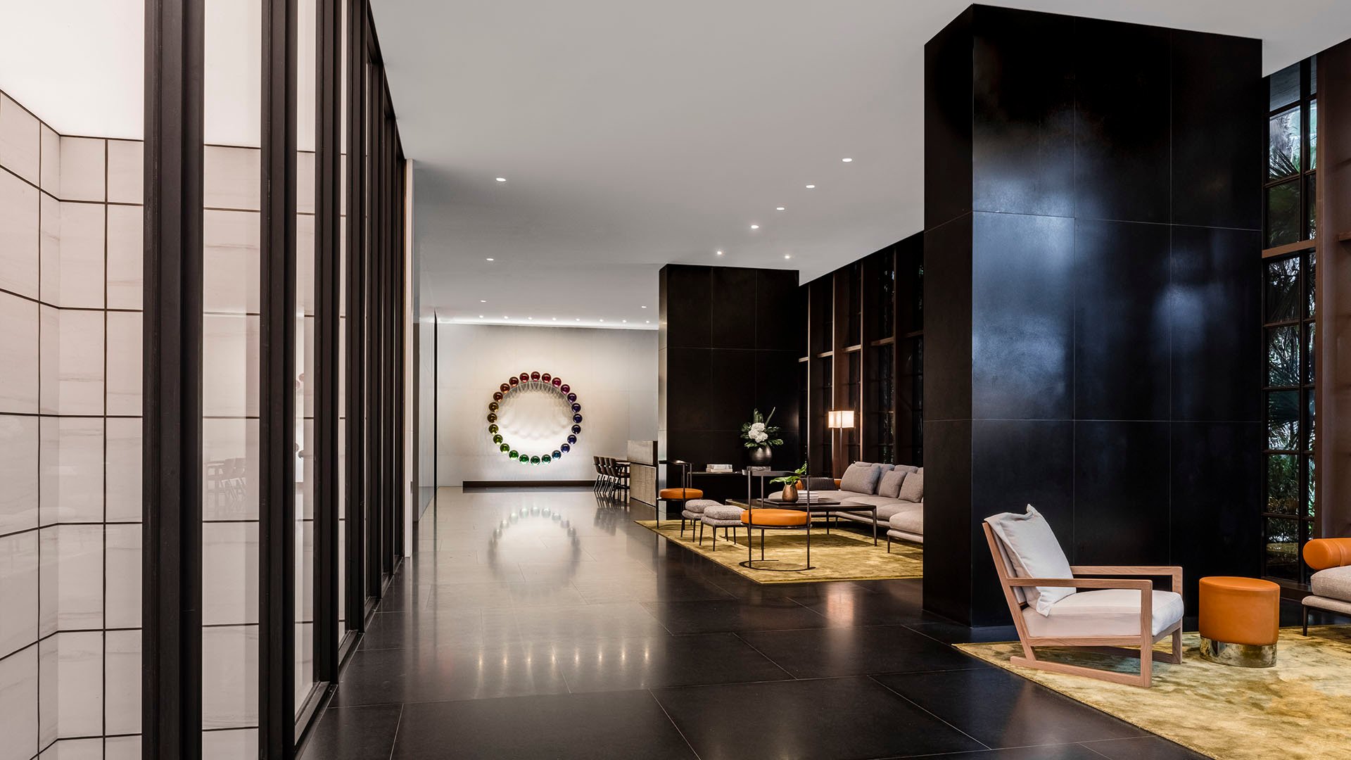 Lobby corridor at Arte Surfside, Surfside, Florida, where luxury and ultra luxury condos feature tall black stone columns, paneled walls, and an intimate seating vignette.