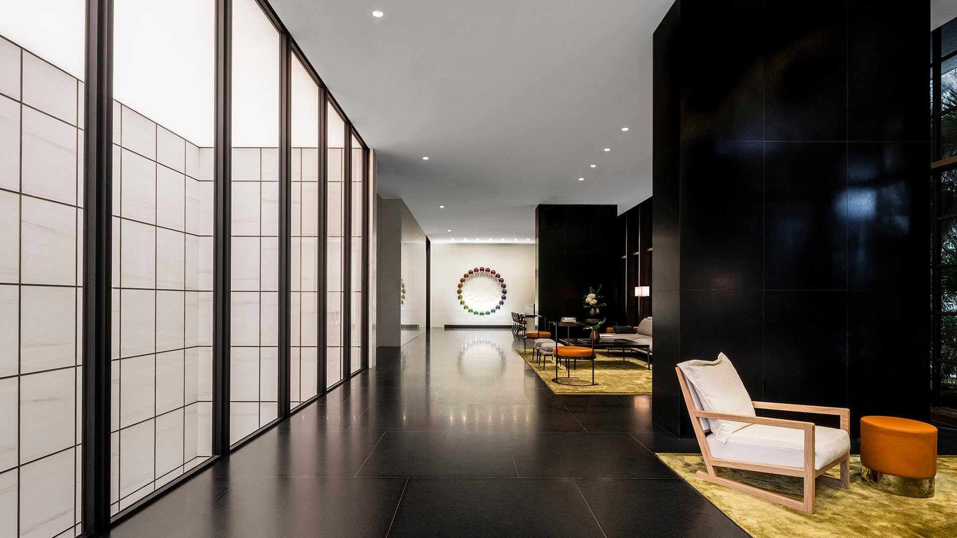 Lobby gallery corridor at Arte Surfside, Surfside, Florida, showing luxury and ultra luxury condos with black stone walls, art, and a refined seating area.