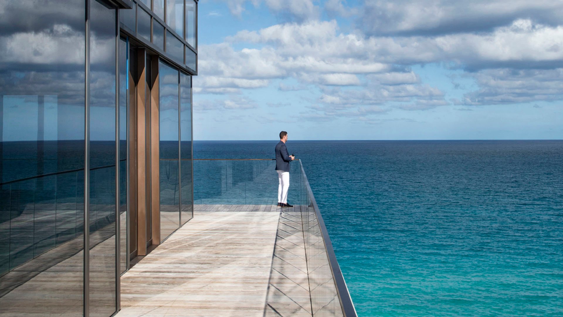 Oceanfront balcony at Arte Surfside, Surfside, Florida, showing luxury and ultra luxury condos with a long glass edge, expansive terrace, and uninterrupted turquoise water views.