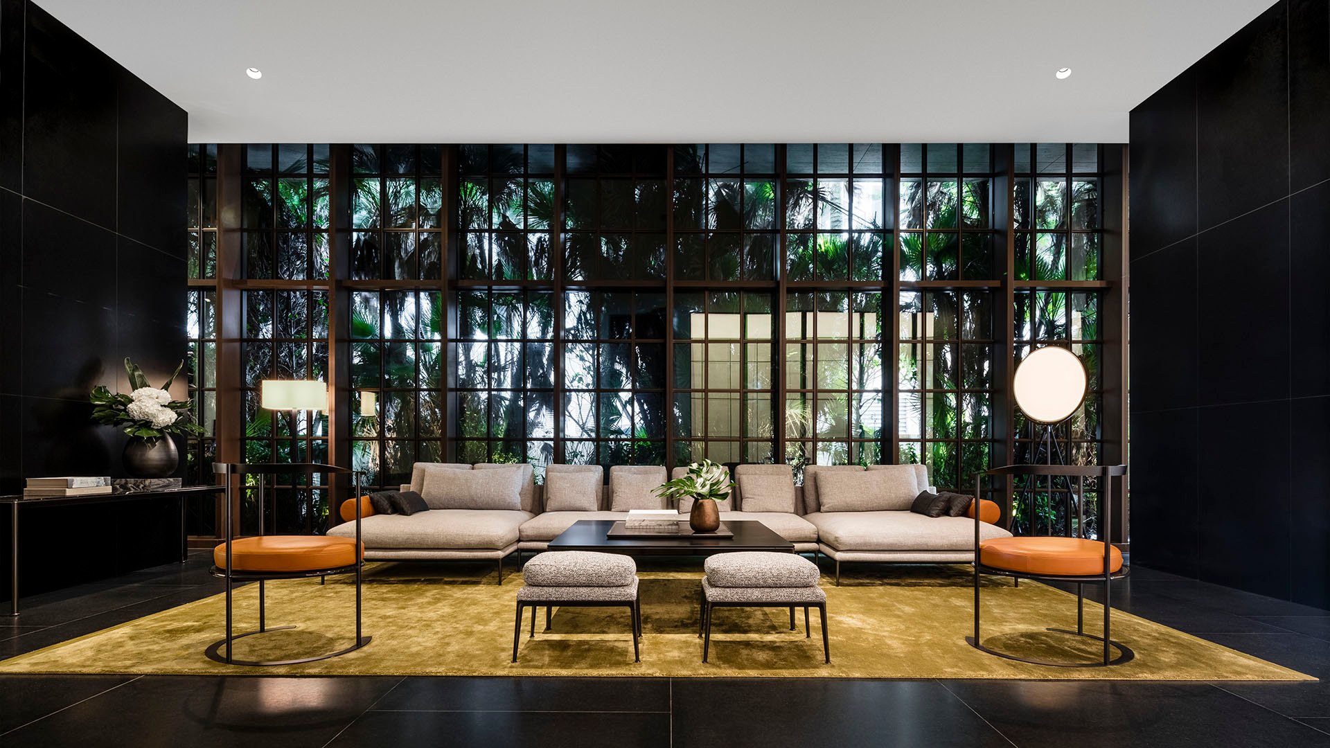 Main lobby at Arte Surfside, Surfside, Florida, presenting luxury and ultra luxury condos with a formal seating area, floor-to-ceiling windows, and a lush garden backdrop.