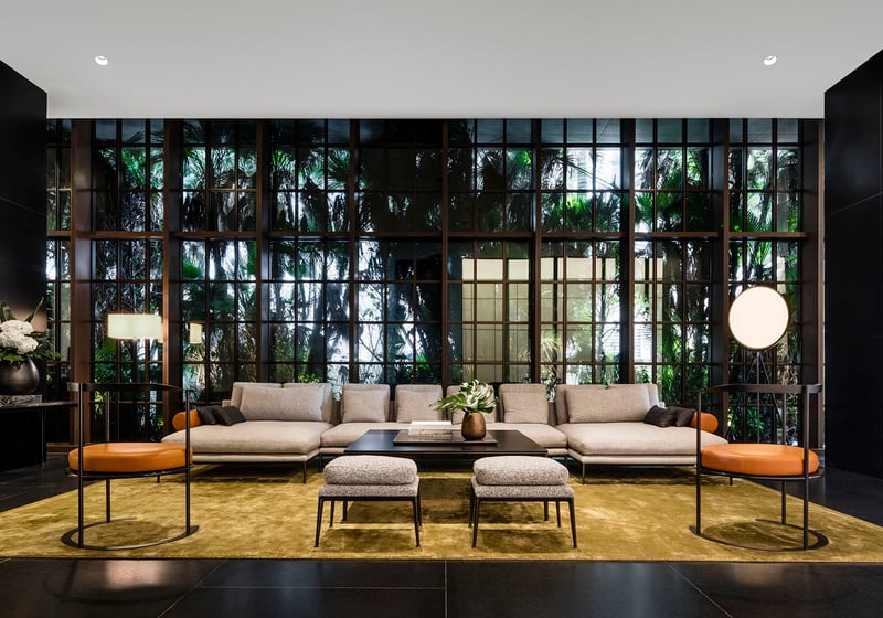 Main lobby at Arte Surfside, Surfside, Florida, presenting luxury and ultra luxury condos with a formal seating area, floor-to-ceiling windows, and a lush garden backdrop.