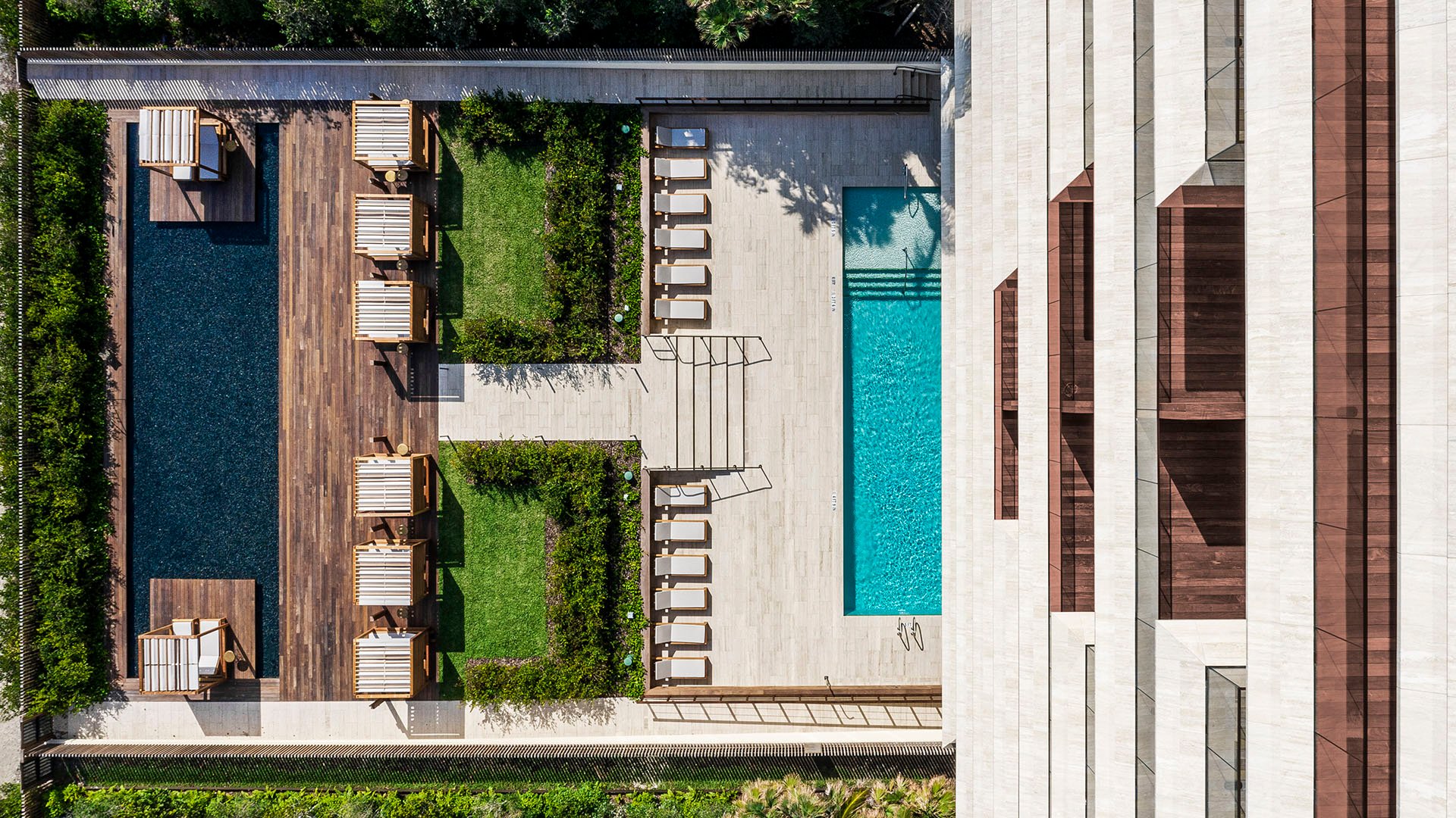Vertical aerial of Arte Surfside, Surfside, Florida, featuring luxury and ultra luxury condos with a lap pool, cabanas, lounge chairs, and landscaped amenity terraces.