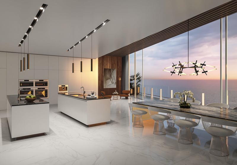 Aston Martin Residences in Downtown Miami luxury and ultra luxury condos chef kitchen with dual islands, dining table, and sunset water views through floor-to-ceiling glass.