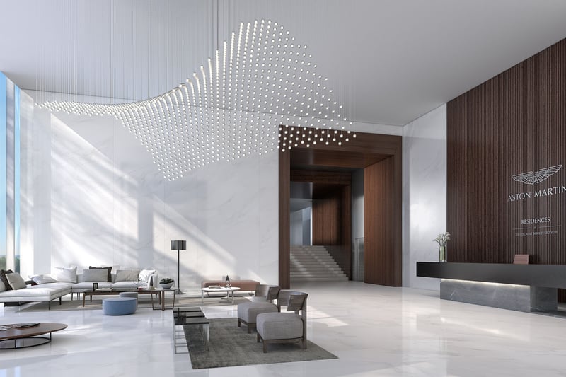 Aston Martin Residences in Downtown Miami luxury and ultra luxury condos grand lobby with a wave-like chandelier, marble floors, lounge seating, and a sleek reception desk.