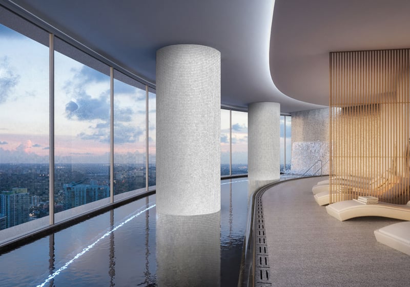 Aston Martin Residences in Downtown Miami luxury and ultra luxury condos indoor spa lounge with a lap pool, chaise seating, warm wood accents, and skyline views at dusk.