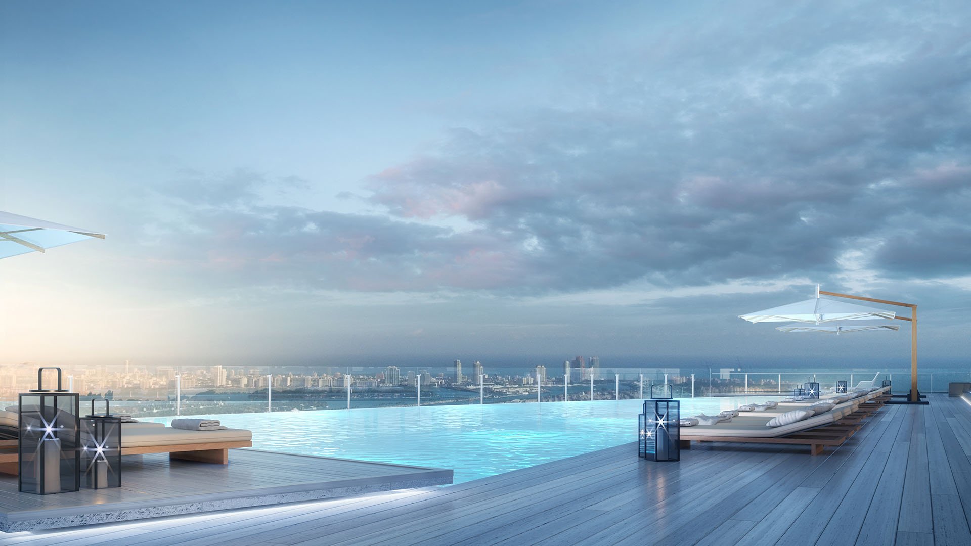 Aston Martin Residences in Downtown Miami luxury and ultra luxury condos infinity pool terrace with lounge chairs, lanterns, and a panoramic skyline view beneath dramatic clouds.