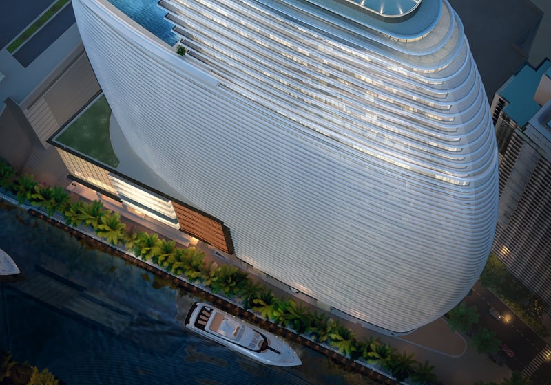 Aston Martin Residences in Downtown Miami luxury and ultra luxury condos top-down aerial of the curved waterfront tower with yachts, palm-lined frontage, and the rooftop pool deck.