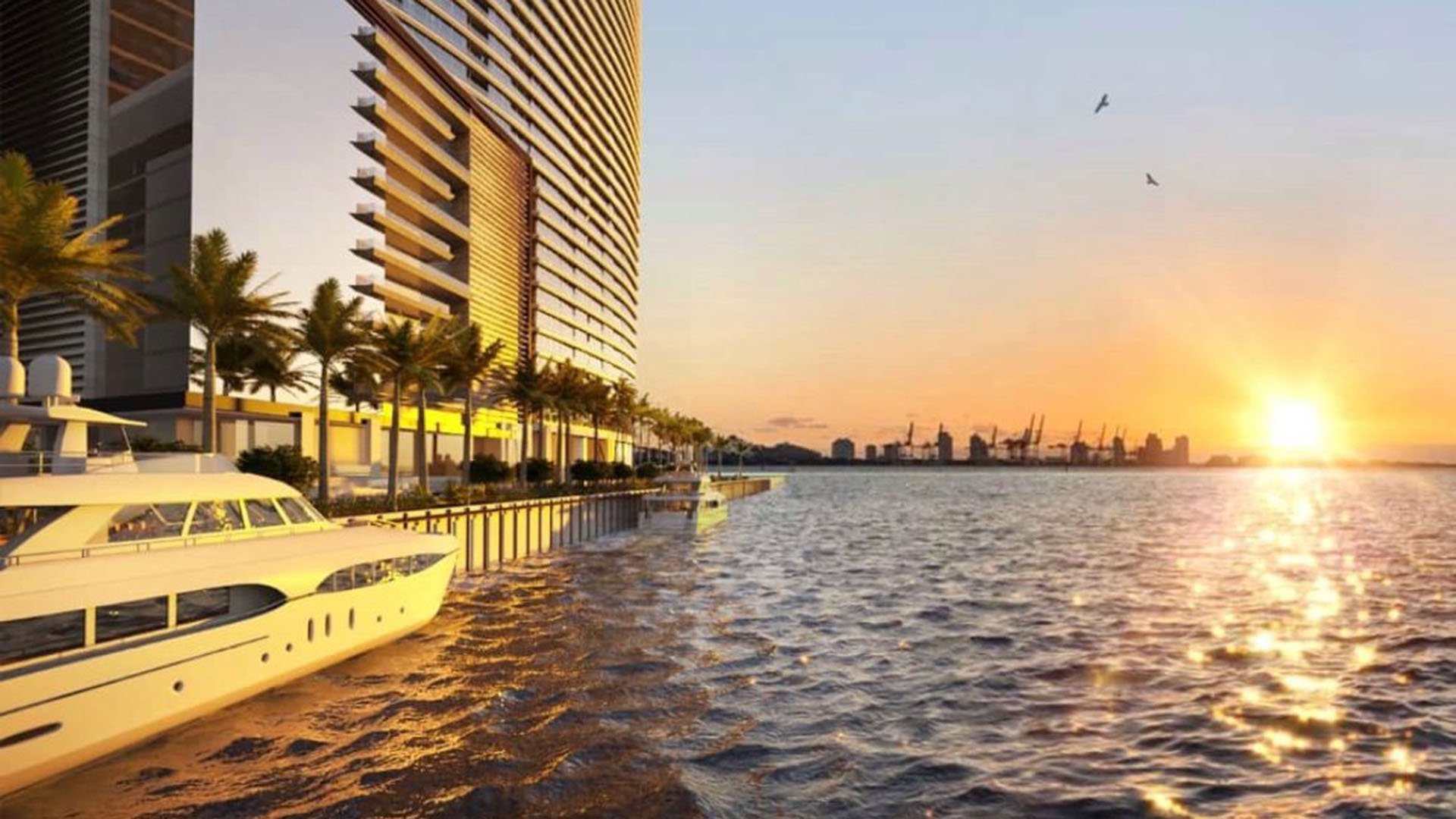Aston Martin Residences in Downtown Miami luxury and ultra luxury condos waterfront promenade at sunset with a yacht, palm-lined edge, and the skyline glowing across the water.