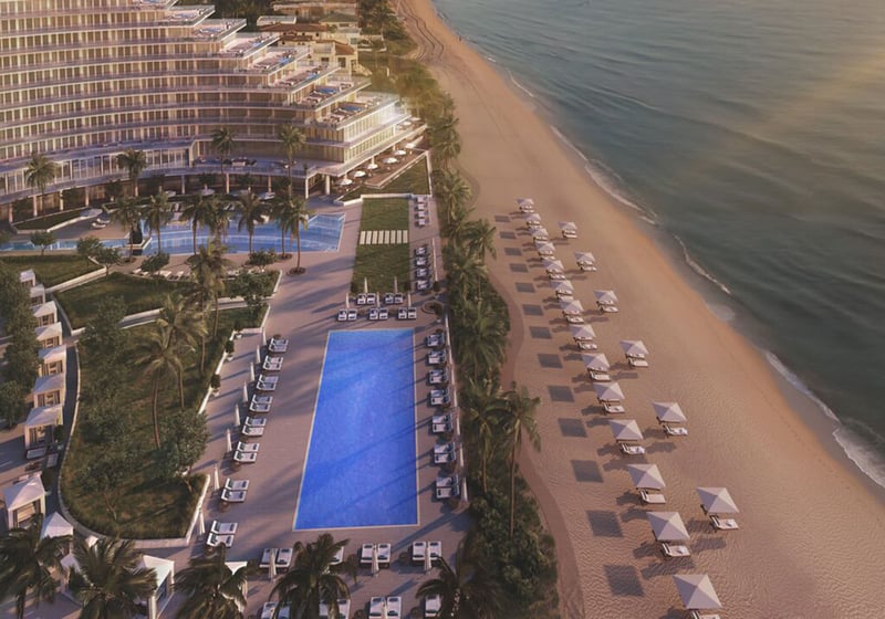 Auberge Beach Residences, Fort Lauderdale luxury and ultra luxury condos aerial view of a long beachfront pool deck with rows of cabanas, palm trees, and a quiet sandy shoreline beside the ocean.