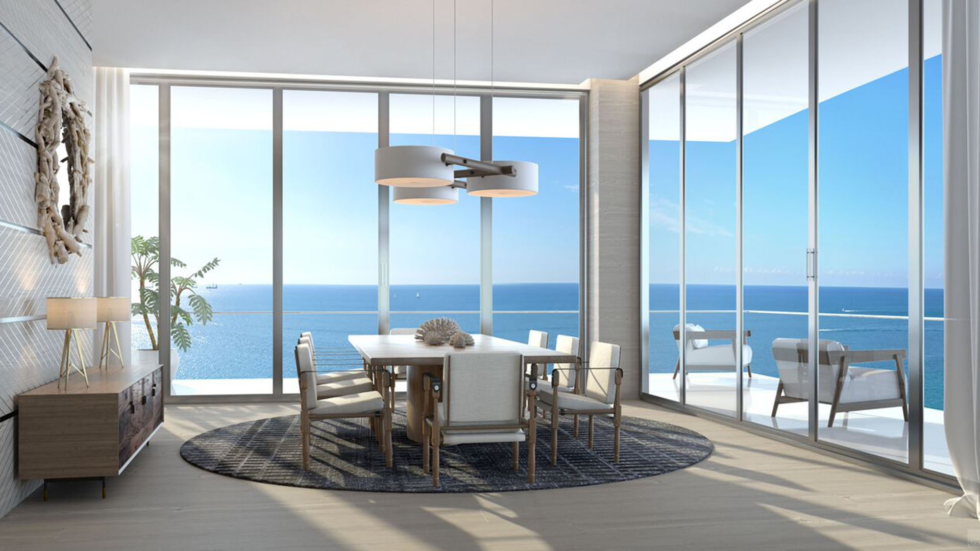 Auberge Beach Residences, Fort Lauderdale luxury and ultra luxury condos corner dining room with wraparound glass, terrace access, and expansive ocean views in a bright coastal interior.