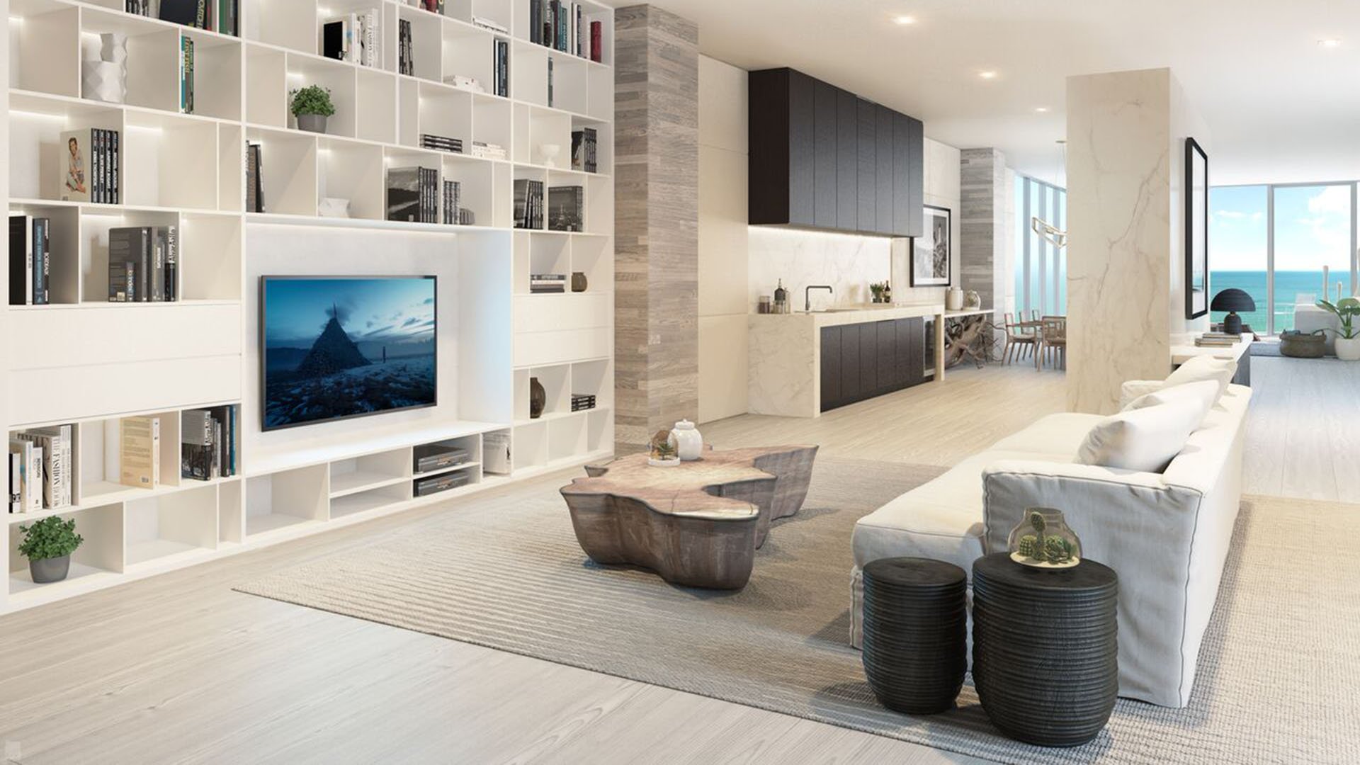 Auberge Beach Residences, Fort Lauderdale luxury and ultra luxury condos family room with a built-in media wall, open kitchen, soft neutral furnishings, and an ocean view in the distance.