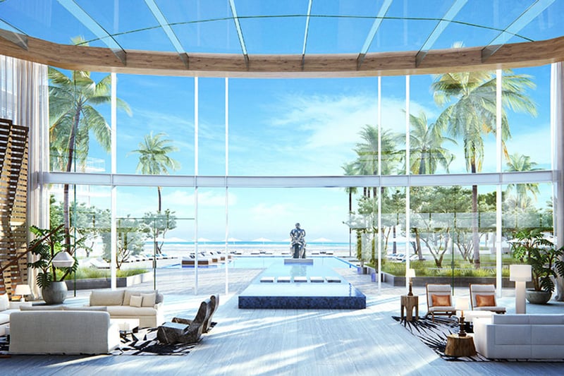 Auberge Beach Residences, Fort Lauderdale luxury and ultra luxury condos grand lobby with soaring glass, a reflecting pool, sculpture, palm trees, and an ocean view beyond.