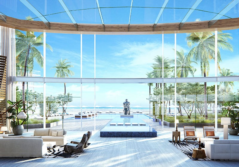 Auberge Beach Residences, Fort Lauderdale luxury and ultra luxury condos grand lobby with soaring glass, a reflecting pool, sculpture, palm trees, and an ocean view beyond.
