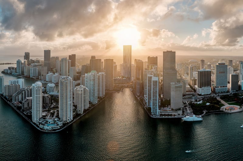 Baccarat Residences in Brickell, Miami, luxury and ultra luxury condos featuring a golden-hour aerial over the waterfront peninsula, bay water, boats, and the downtown skyline.