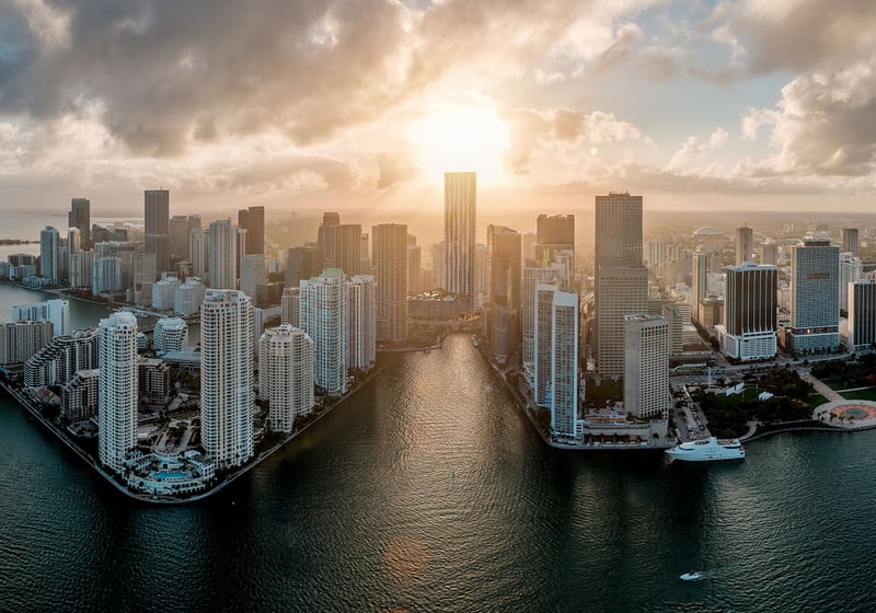 Baccarat Residences in Brickell, Miami, luxury and ultra luxury condos featuring a golden-hour aerial over the waterfront peninsula, bay water, boats, and the downtown skyline.