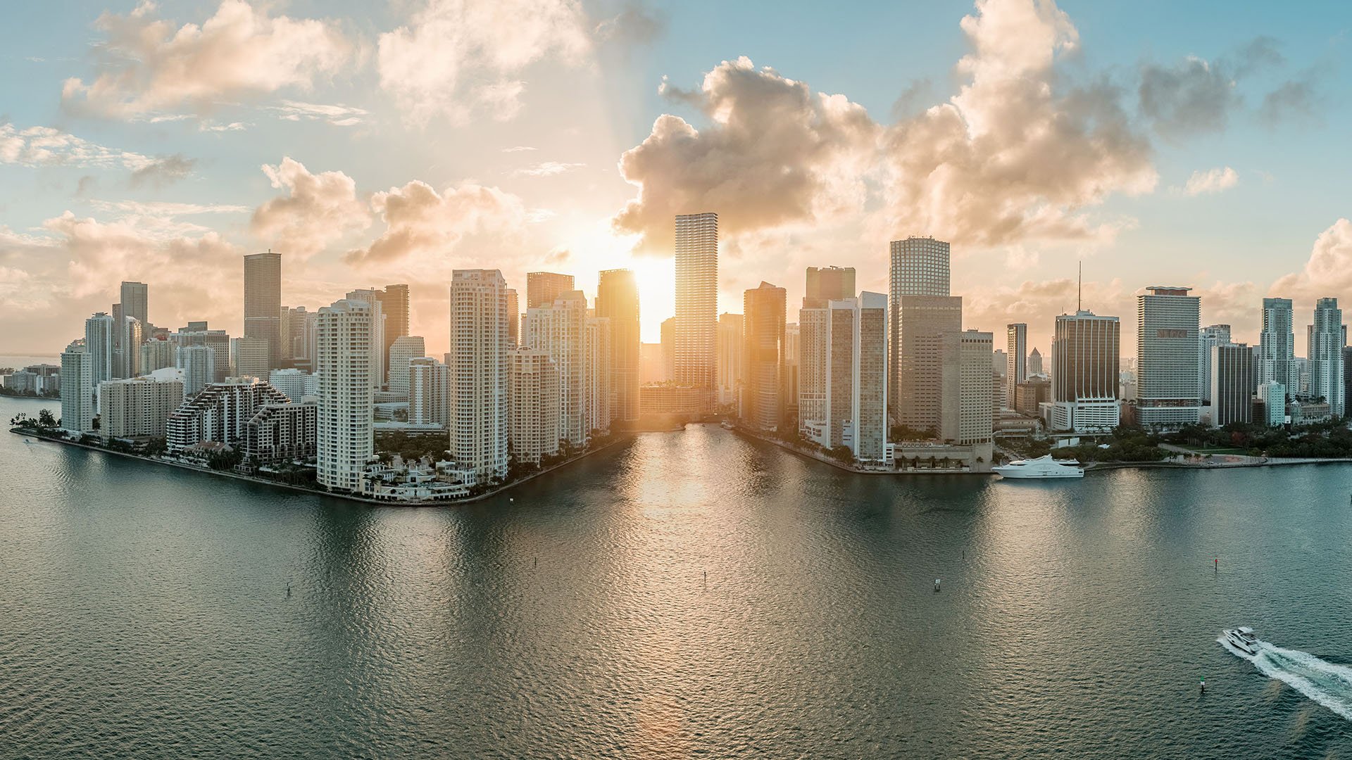 Baccarat Residences in Brickell, Miami, luxury and ultra luxury condos featuring a golden-hour panorama of the waterfront skyline, wide bay views, and sunlight reflecting across the water.