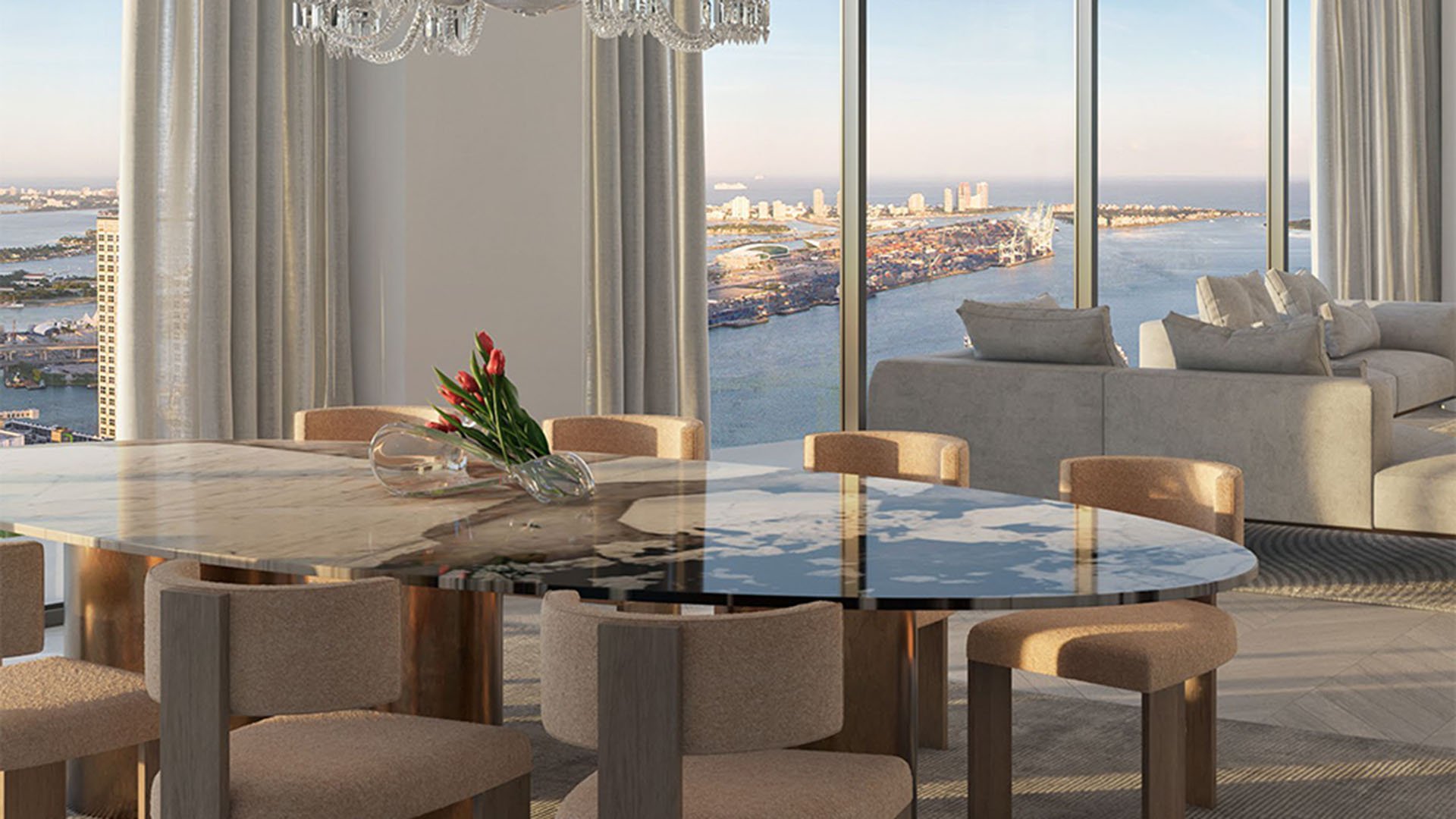 Baccarat Residences in Brickell, Miami, luxury and ultra luxury condos featuring a marble dining table, upholstered chairs, a chandelier, and waterfront lounge views through tall windows.