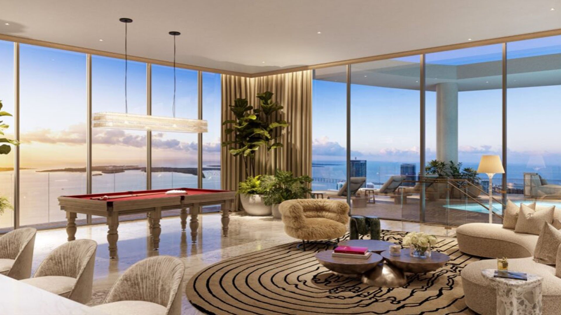 Baccarat Residences in Brickell, Miami, luxury and ultra luxury condos featuring a penthouse game lounge, billiards table, curved seating, a terrace pool beyond, and expansive water views at golden hour.