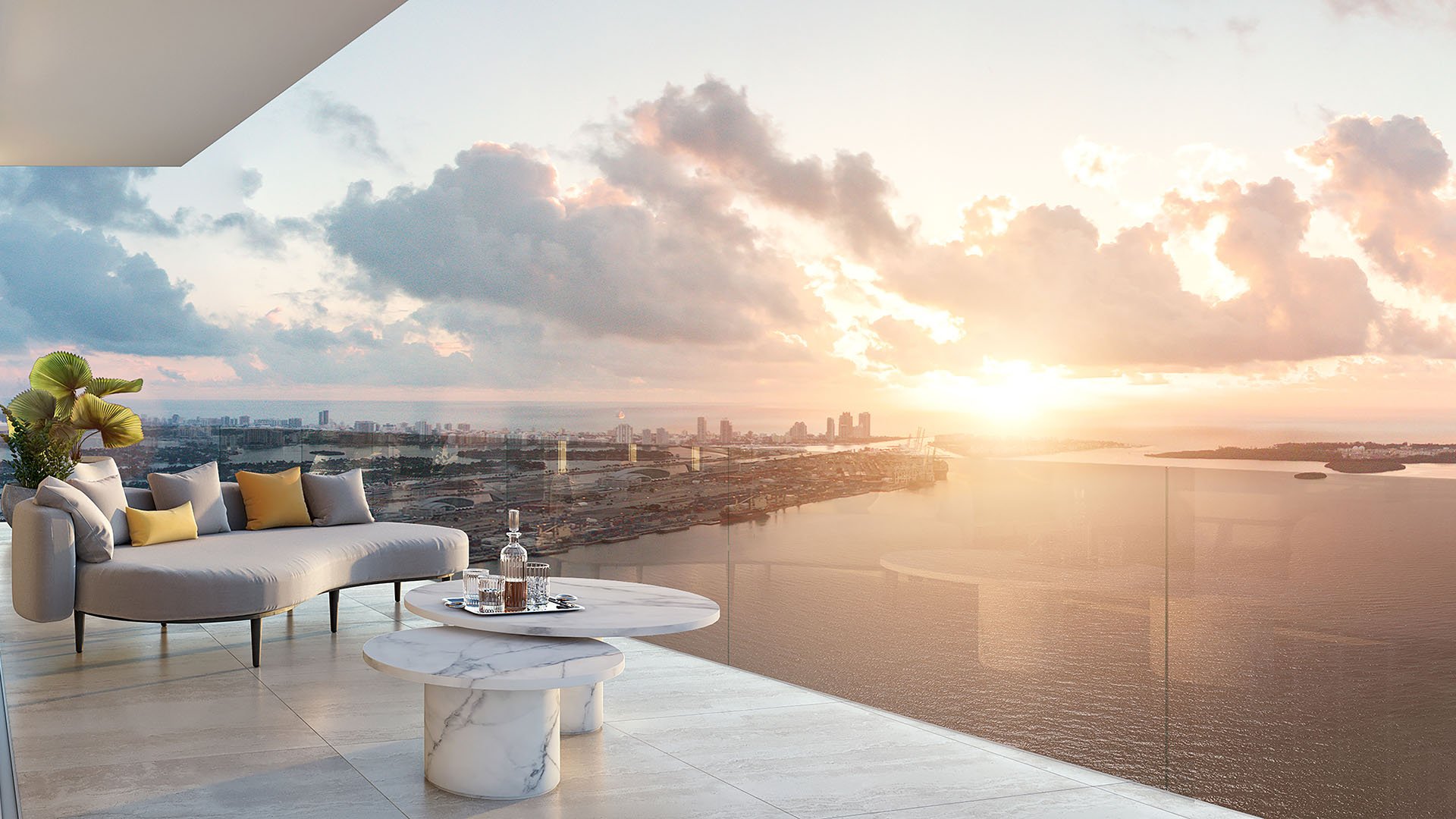 Baccarat Residences in Brickell, Miami, luxury and ultra luxury condos featuring a sunlit terrace lounge, a curved outdoor sofa, marble tables, glass railing, and expansive water views.