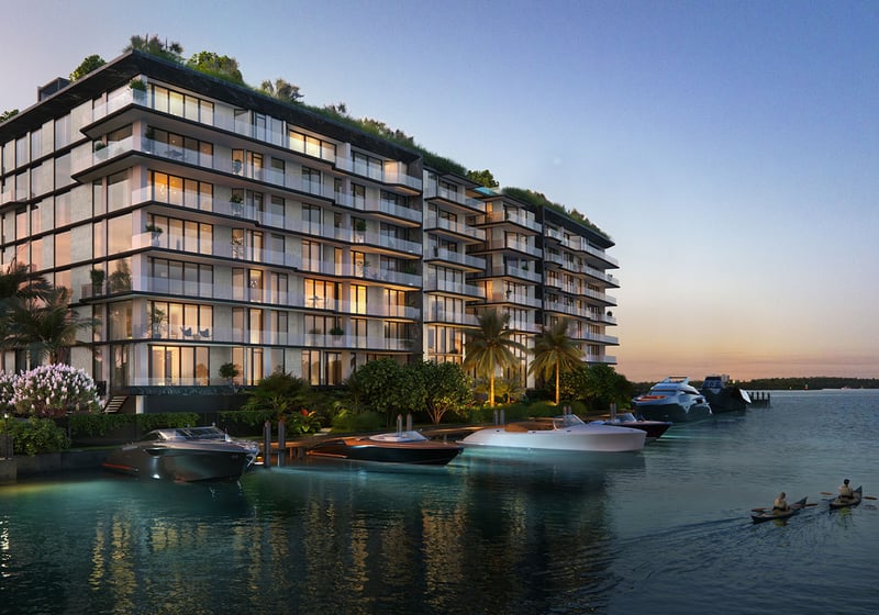 Sunset waterfront exterior of Bay Harbor Towers, Bay Harbor Islands, Florida with marina dock, yachts and illuminated glass balconies, promoting luxury and ultra luxury preconstruction condos on the bay.