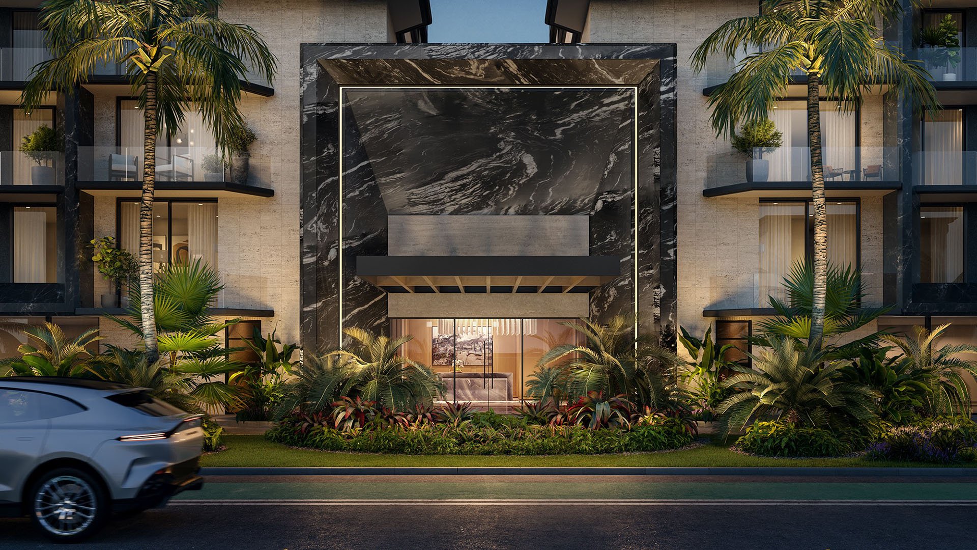 Night view of Bay Harbor Towers in Bay Harbor Islands, Florida featuring dramatic marble entry portal, illuminated balconies, palm landscaping and street arrival, showcasing luxury and ultra luxury preconstruction condos.