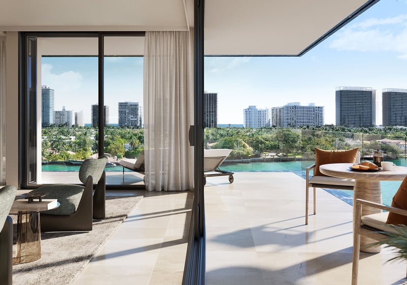 Bay Harbor Towers Bay Harbor Islands waterfront living room and terrace with lounge seating, glass railing and canal-to-ocean skyline views, highlighting luxury and ultra luxury preconstruction condos in Miami.