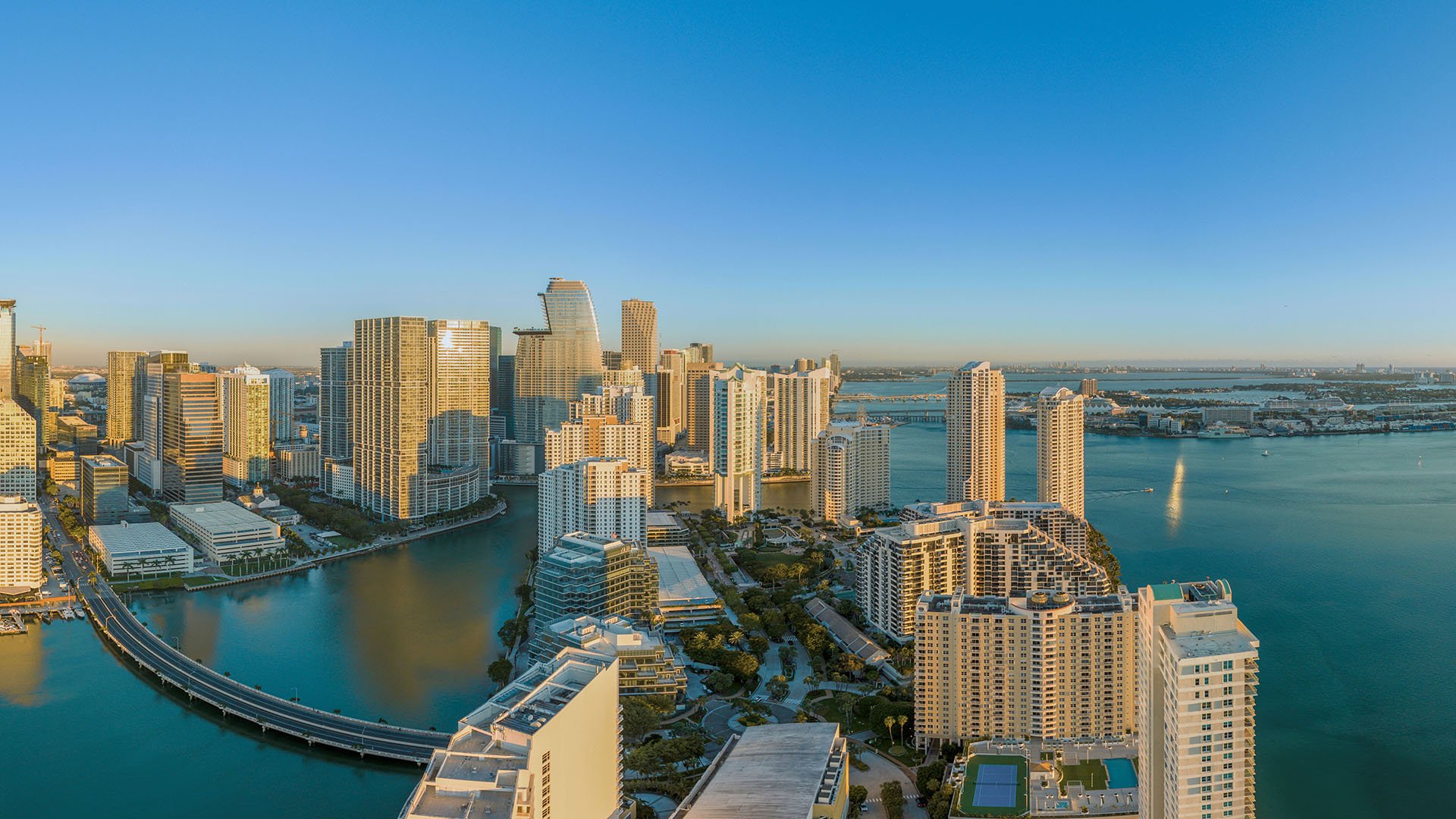Panoramic aerial of Brickell Key, Brickell skyline and Biscayne Bay with bridge and islands, showcasing luxury and ultra luxury condos with preconstruction and resale choices in Miami, Florida.