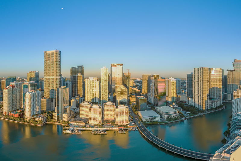 Daytime aerial of Downtown Miami and Brickell waterfront towers with Brickell Key Bridge over Biscayne Bay, showcasing luxury and ultra luxury condos with preconstruction and resale inventory in Miami, Florida.
