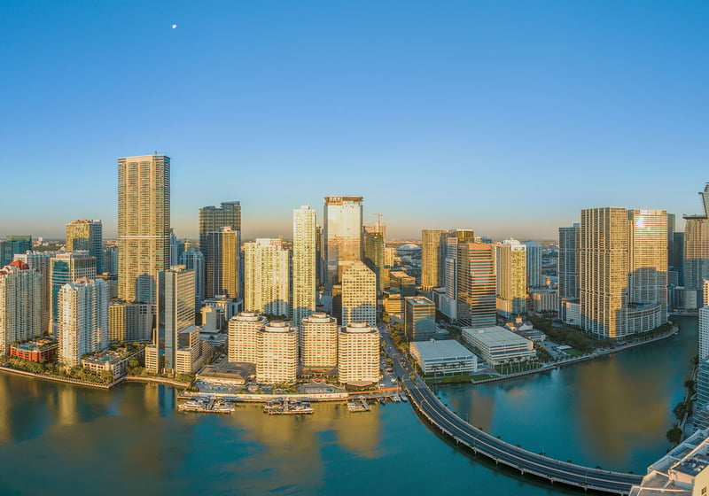 Daytime aerial of Downtown Miami and Brickell waterfront towers with Brickell Key Bridge over Biscayne Bay, showcasing luxury and ultra luxury condos with preconstruction and resale inventory in Miami, Florida.