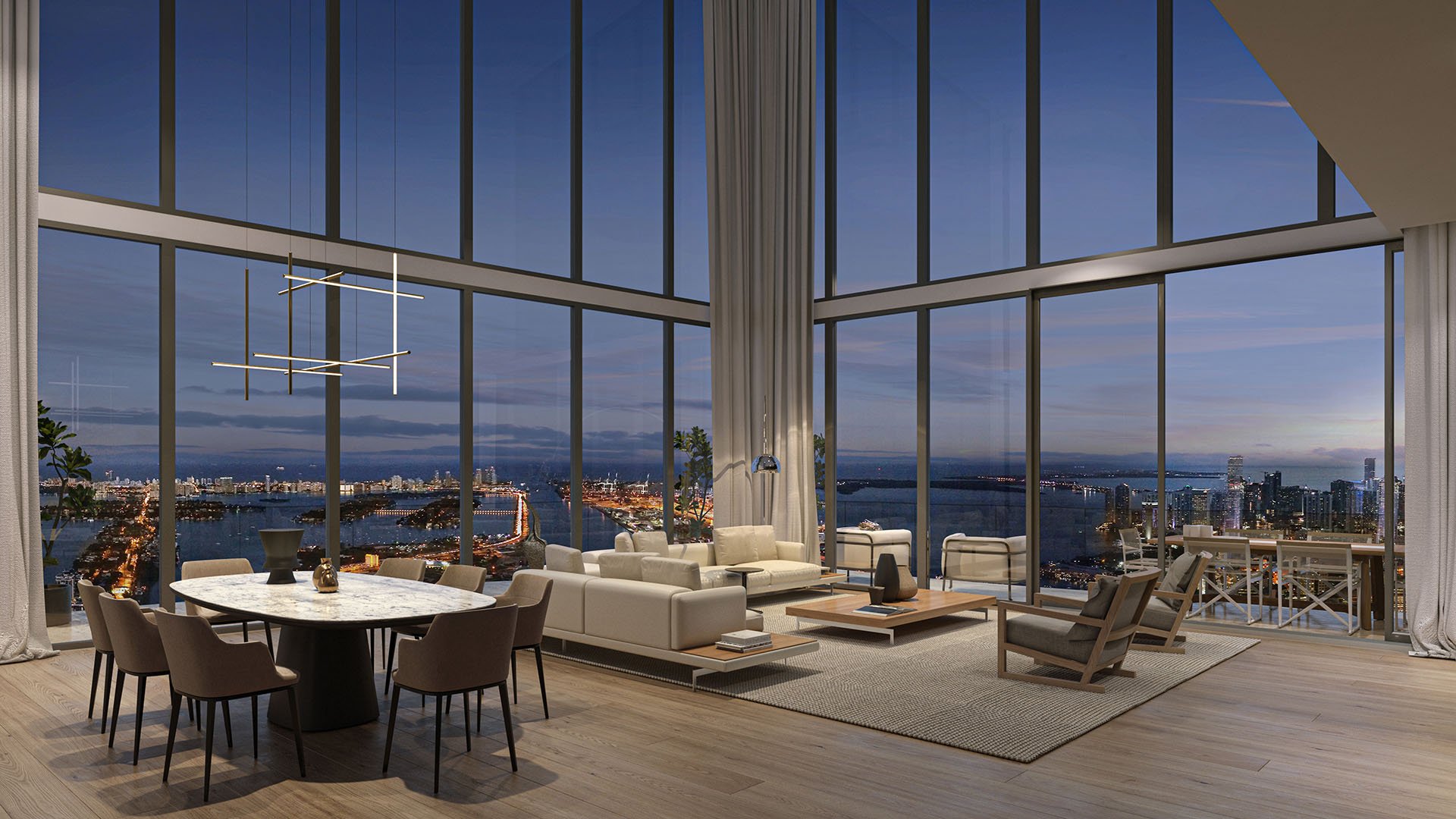 Casa Bella Downtown Miami double-height living and dining room at night with panoramic skyline and bay lights, modern chandelier and terrace, highlighting luxury and ultra luxury preconstruction condos views.