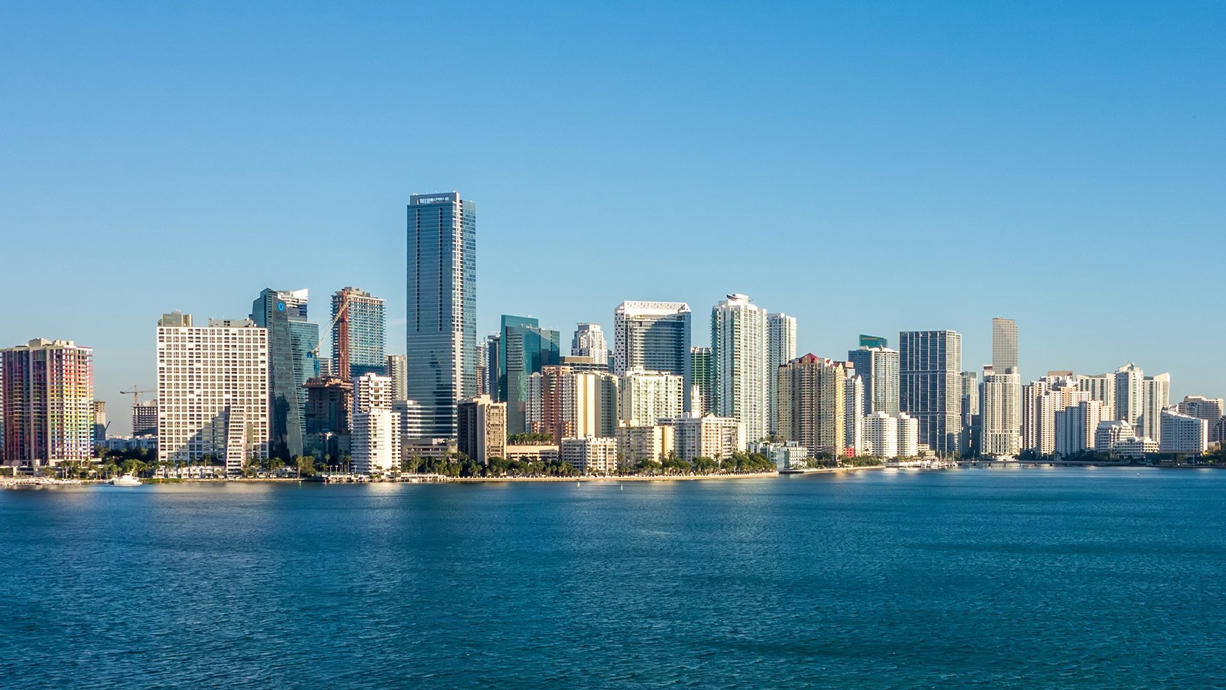 Miami skyline by day with clear views of Biscayne Bay and high‑rises—central hub for luxury and ultra luxury condos, preconstruction and resale.