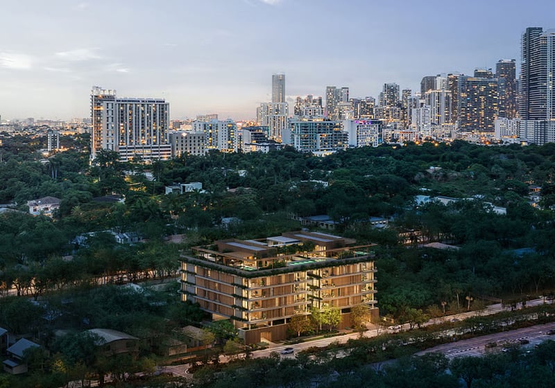 Colette Residences in Brickell luxury ultra luxury condos seen from above at dusk, with the mid-rise building illuminated amid lush greenery and the skyline in the background.