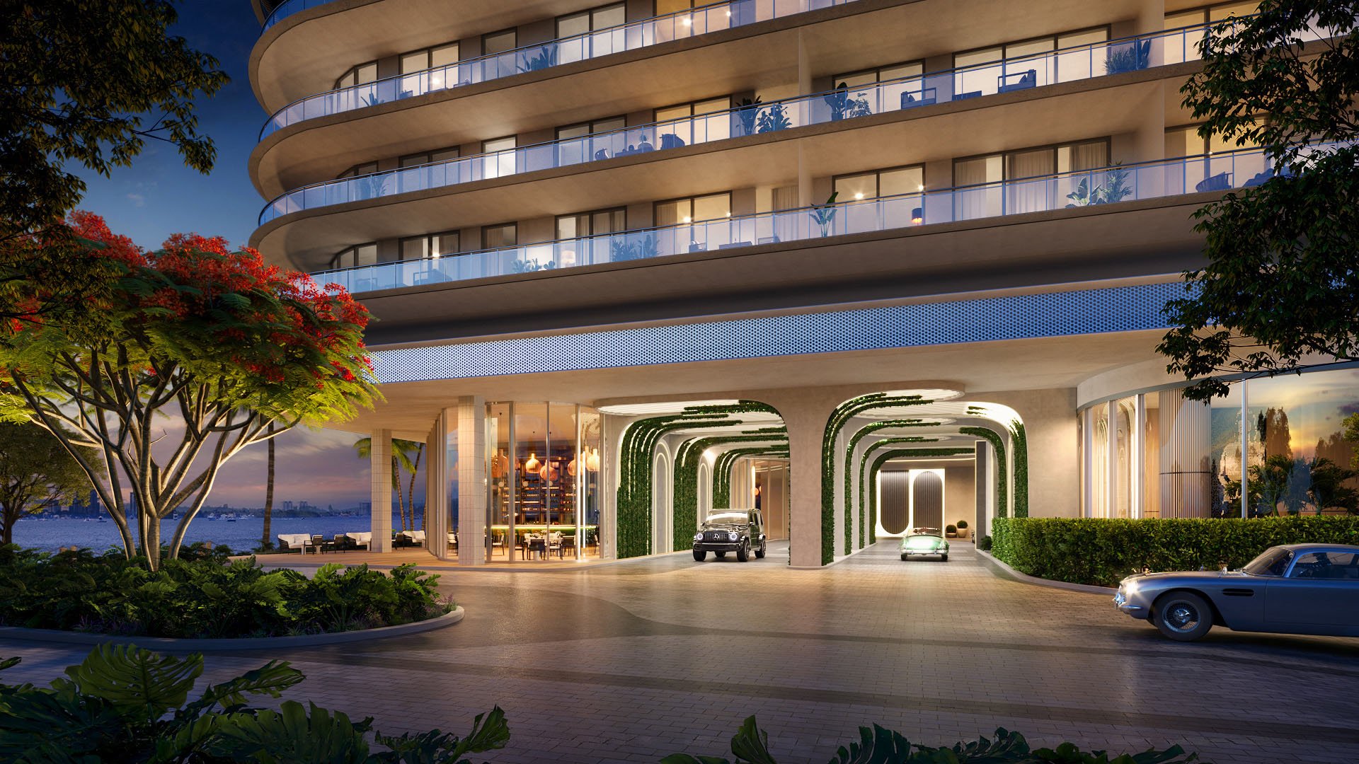 Curved porte cochere entrance with illuminated canopy arches and lush landscaping at Continuum Club and Residences in North Bay Village, a preconstruction luxury and ultra luxury condos development on the waterfront.