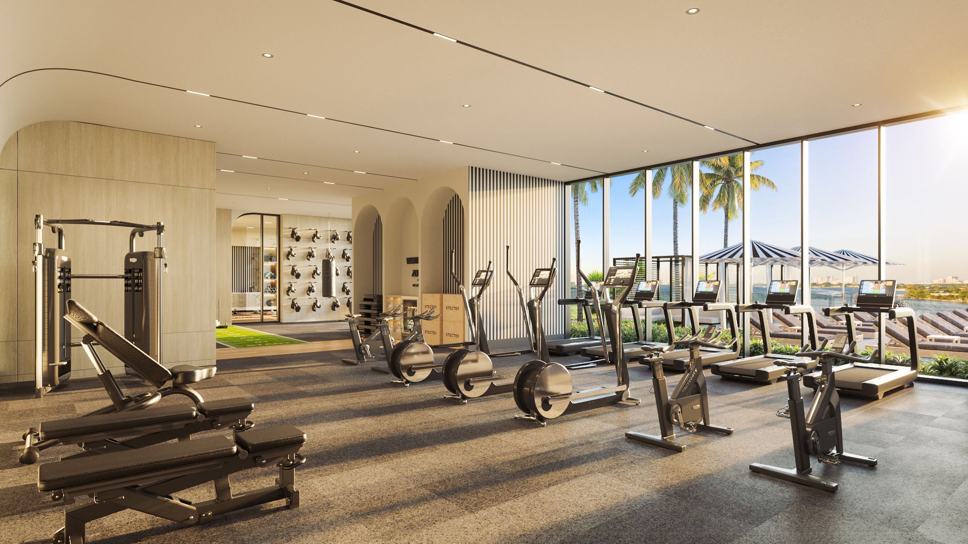 Fitness center with strength and cardio equipment overlooking the pool deck at Continuum Club and Residences in North Bay Village, a preconstruction luxury and ultra luxury condos development with bright waterfront wellness spaces.