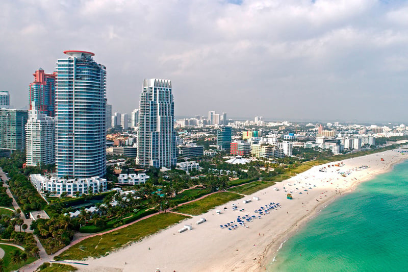 Aerial beachfront view of Continuum on South Beach, Miami Beach, Florida, showing luxury and ultra luxury condos along the white-sand shoreline with turquoise water and the South Beach skyline extending into the distance.