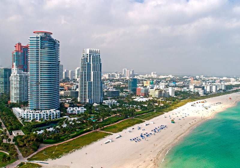 Aerial beachfront view of Continuum on South Beach, Miami Beach, Florida, showing luxury and ultra luxury condos along the white-sand shoreline with turquoise water and the South Beach skyline extending into the distance.